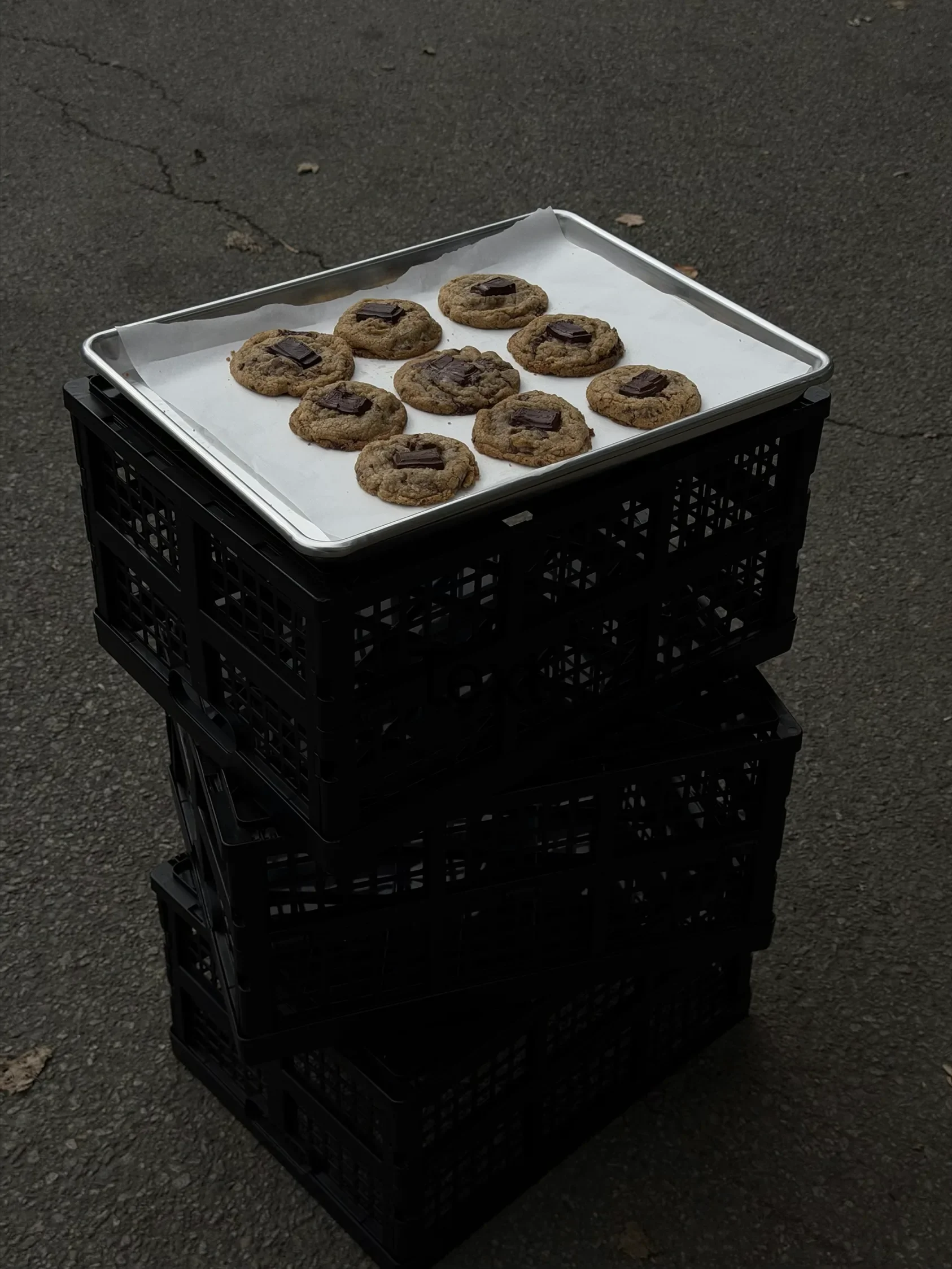 A tray of chocolate chunk cookies on a stack of black crates